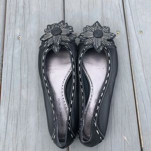 Black leather flats with flower detail.